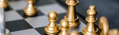 Close-up of golden chess pieces on a chessboard, ready for a strategic move.